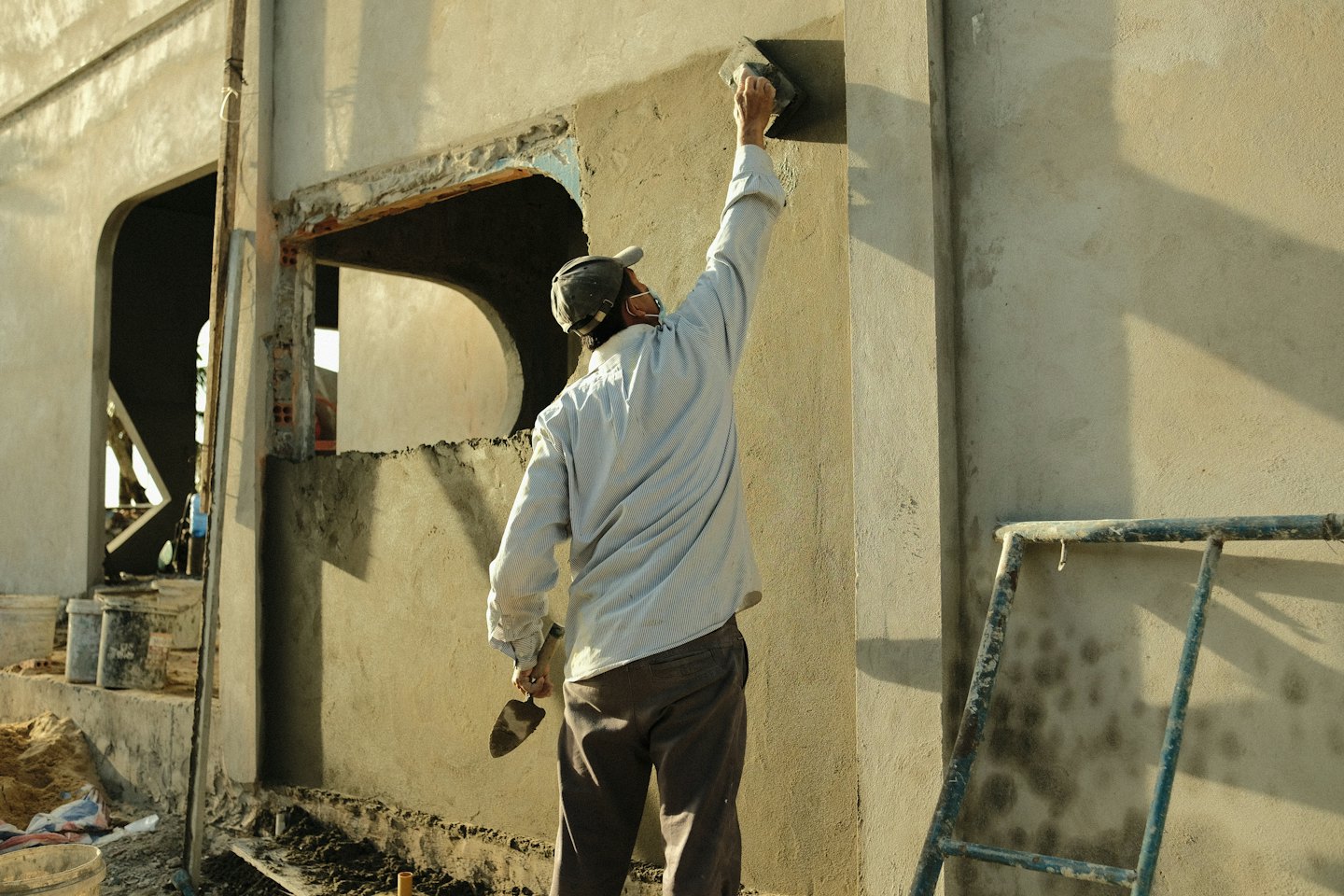 Construction worker plastering a building exterior wall.
