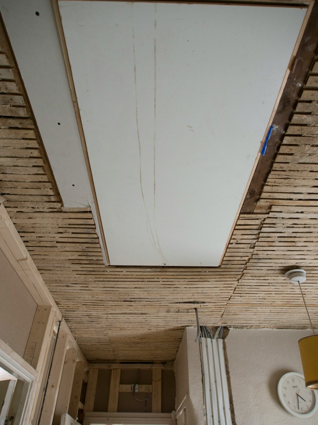 Construction workers renovate a ceiling with wooden beams and plasterboard.
